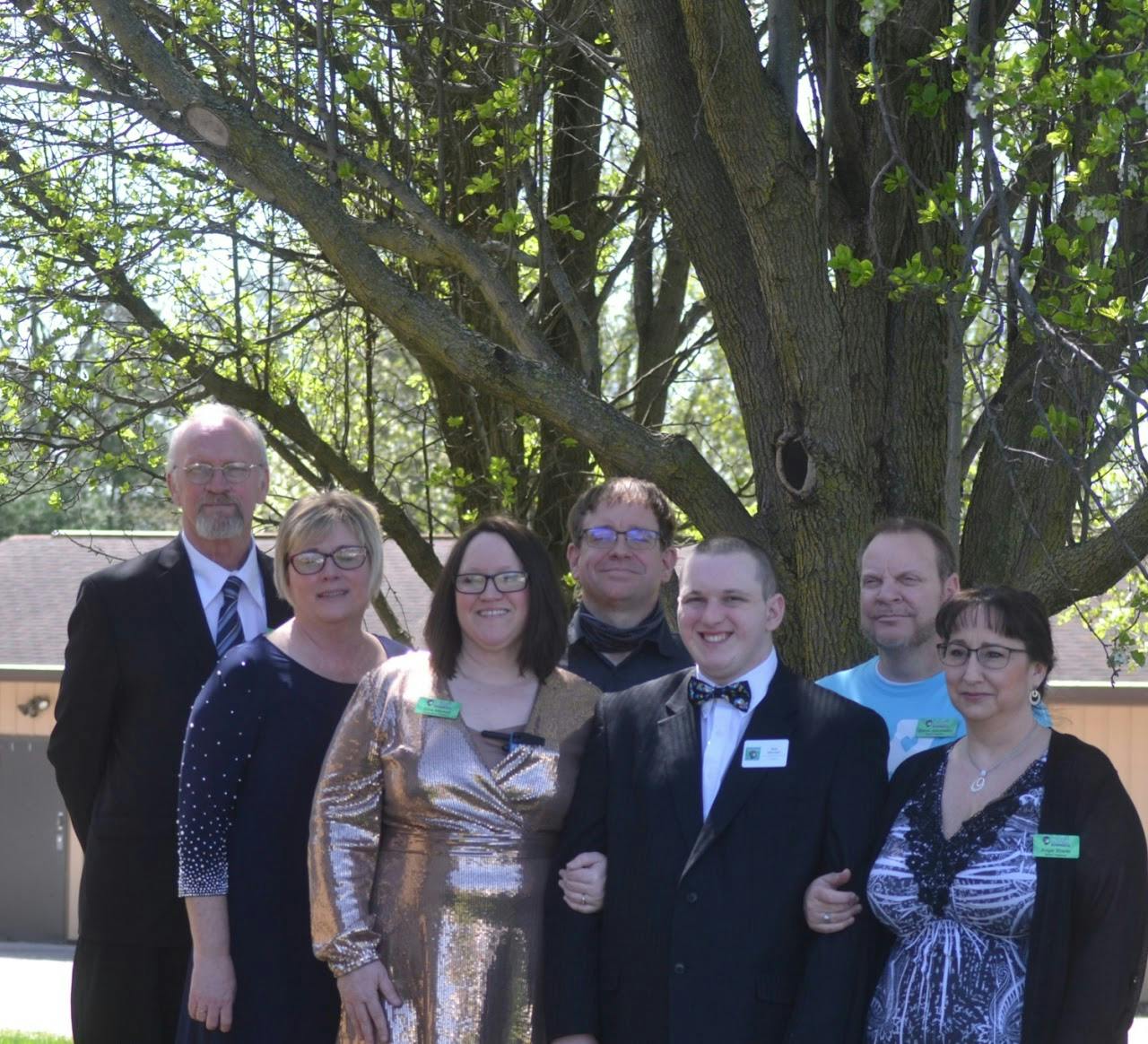 Sam and Gina standing with the Board of Directors in front of a tree.
